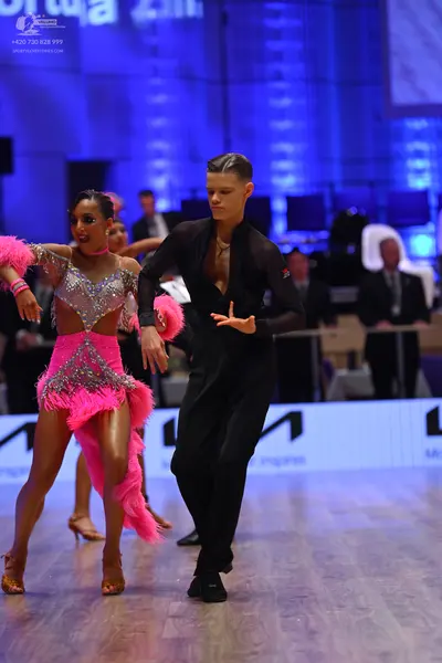 Dancesport competitor: Female dancer: pink and silver latin dress with sequins, mesh, and long pink fri