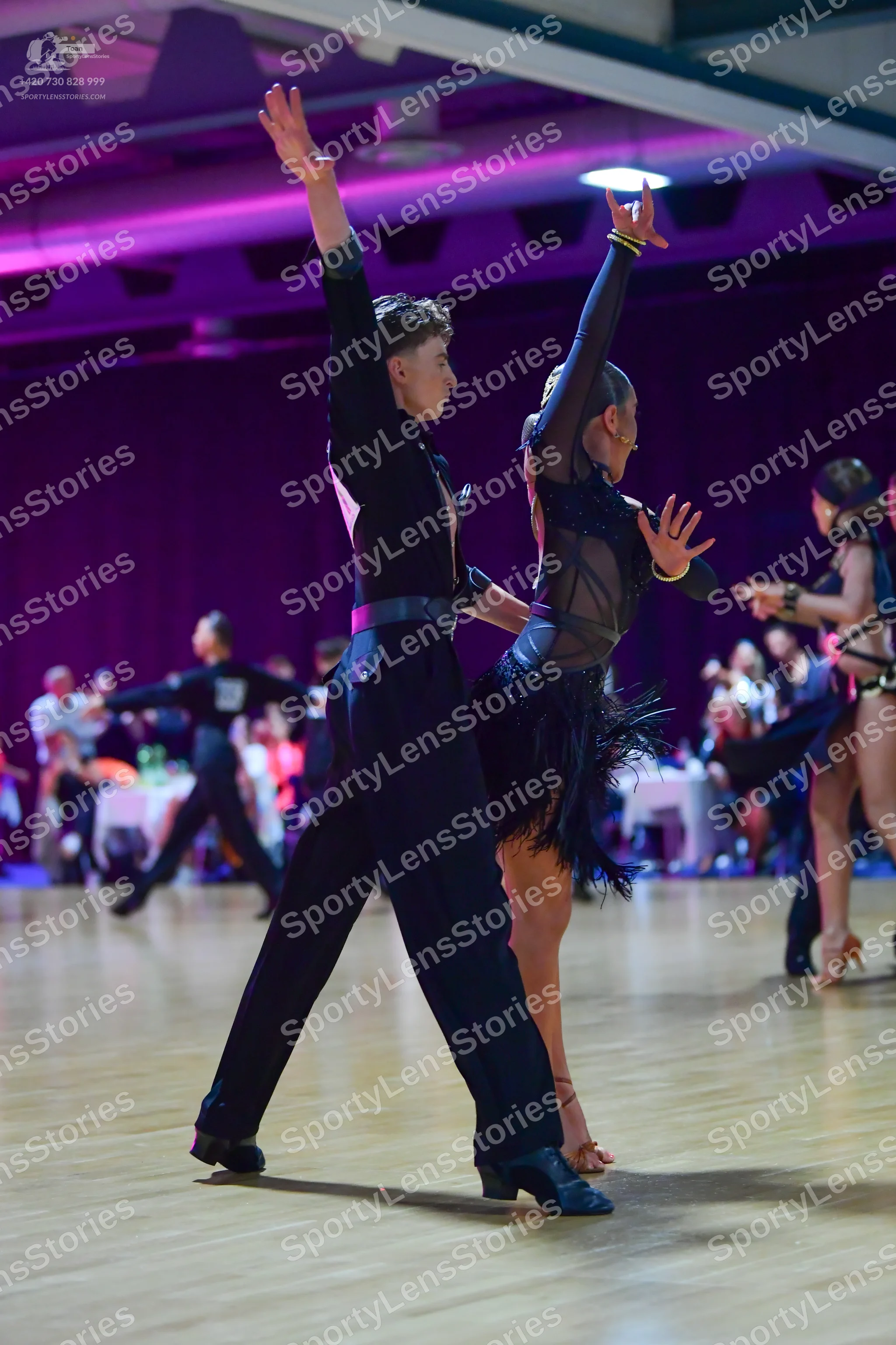 Dancesport competitor: Foreground male dancer: black long-sleeved shirt and black trousers
