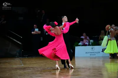 Dancesport competitor: Female dancer in foreground: fuchsia latin dress with long sleeves and shimmerin