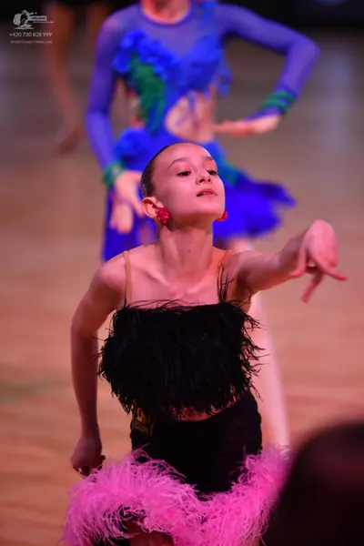 Dancesport competitor: First dancer: blue and green Latin dance dress with long sleeves and textured, r
