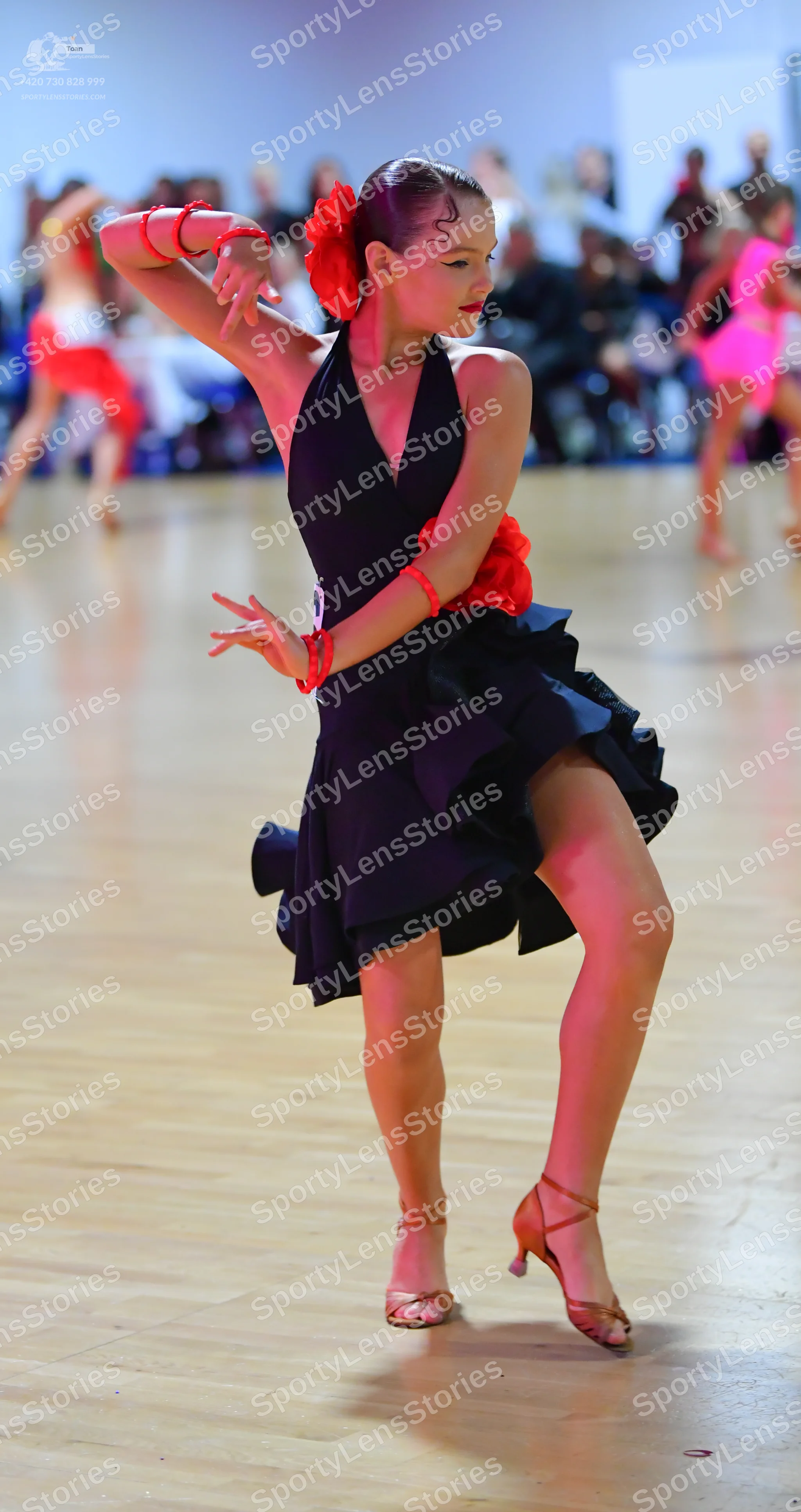 Dancesport competitor: Female dancer: black latin dance dress with a deep V-neck and an asymmetric ruff
