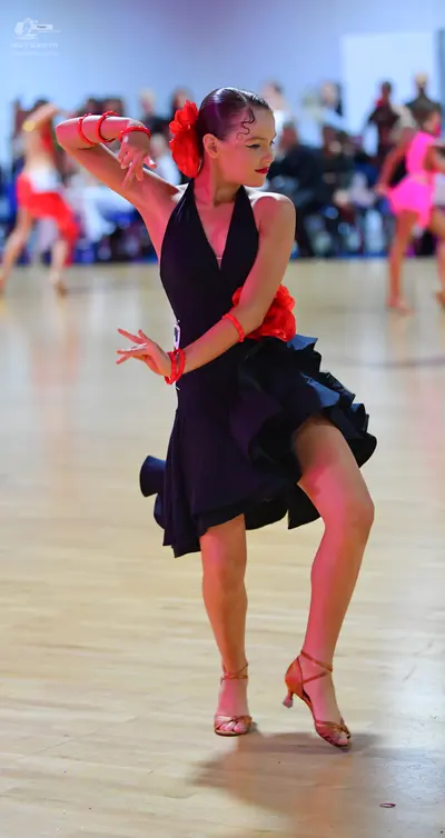 Dancesport competitor: Female dancer: black latin dance dress with a deep V-neck and an asymmetric ruff