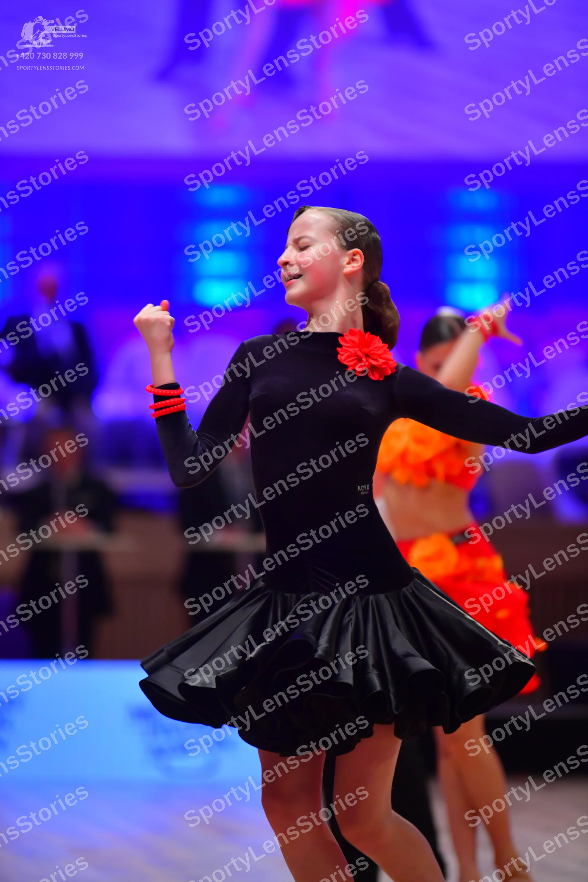 Dancesport competitor: Female dancer 1: black long-sleeved latin dress with a ruffled skirt, a red flow