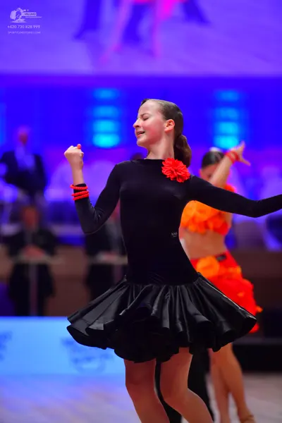 Dancesport competitor: Female dancer 1: black long-sleeved latin dress with a ruffled skirt, a red flow