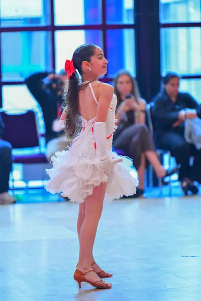 Dancesport competitor: Female dancer: white latin dress with many ruffles and red accents, white gloves