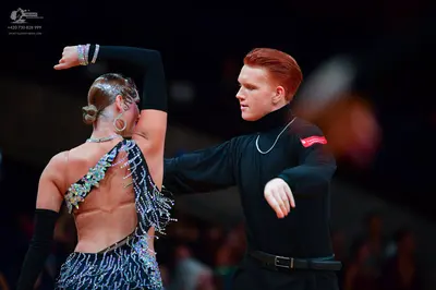 Dancesport competitor: Male dancer: black long-sleeved turtleneck and black trousers with a black belt,