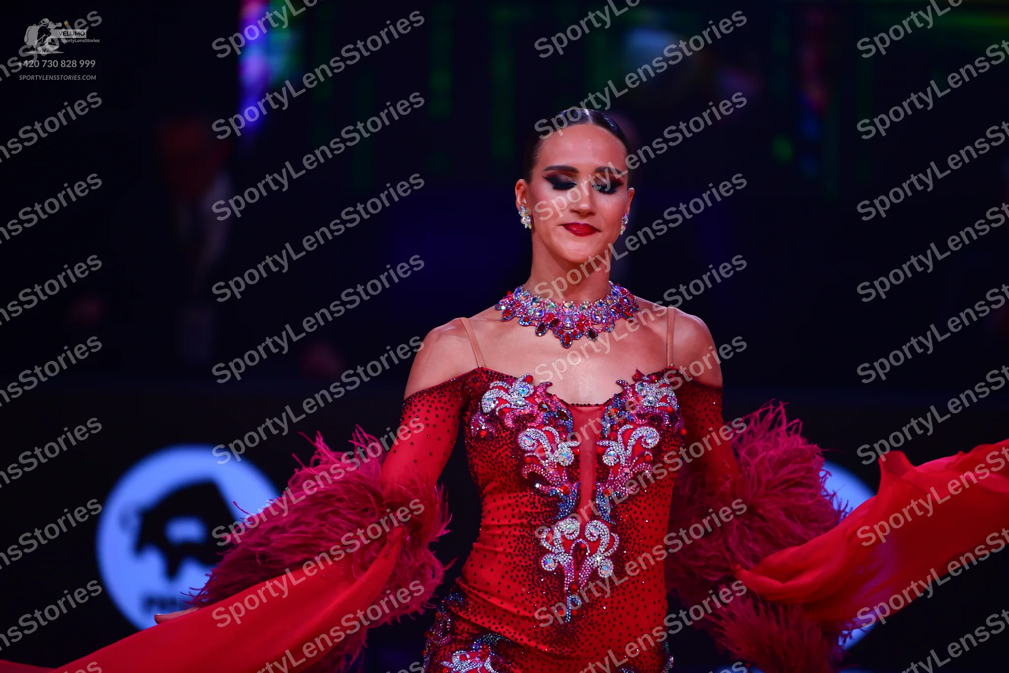 Dancesport competitor: Female dancer: red Latin dress with silver/white sequin patterns, featuring long