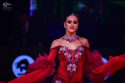 Dancesport competitor: Female dancer: red Latin dress with silver/white sequin patterns, featuring long