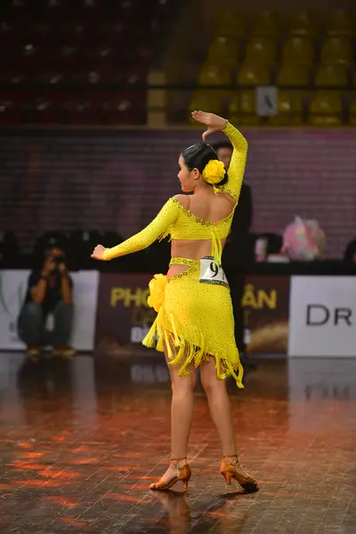 Dancesport competitor: Female dancer: yellow Latin dress with long sleeves and fringe