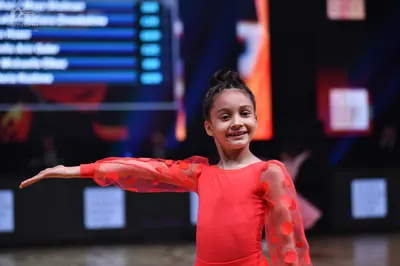 Dancesport competitor: Female dancer: red long-sleeved dance dress with sheer sleeves featuring large r