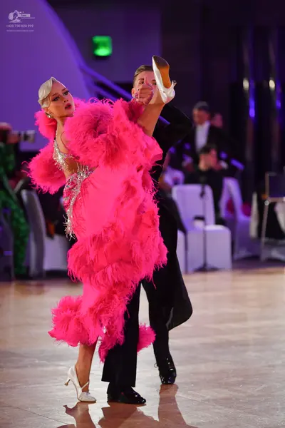 Dancesport competitor: Female dancer: bright pink latin dress heavily adorned with large feathers and s