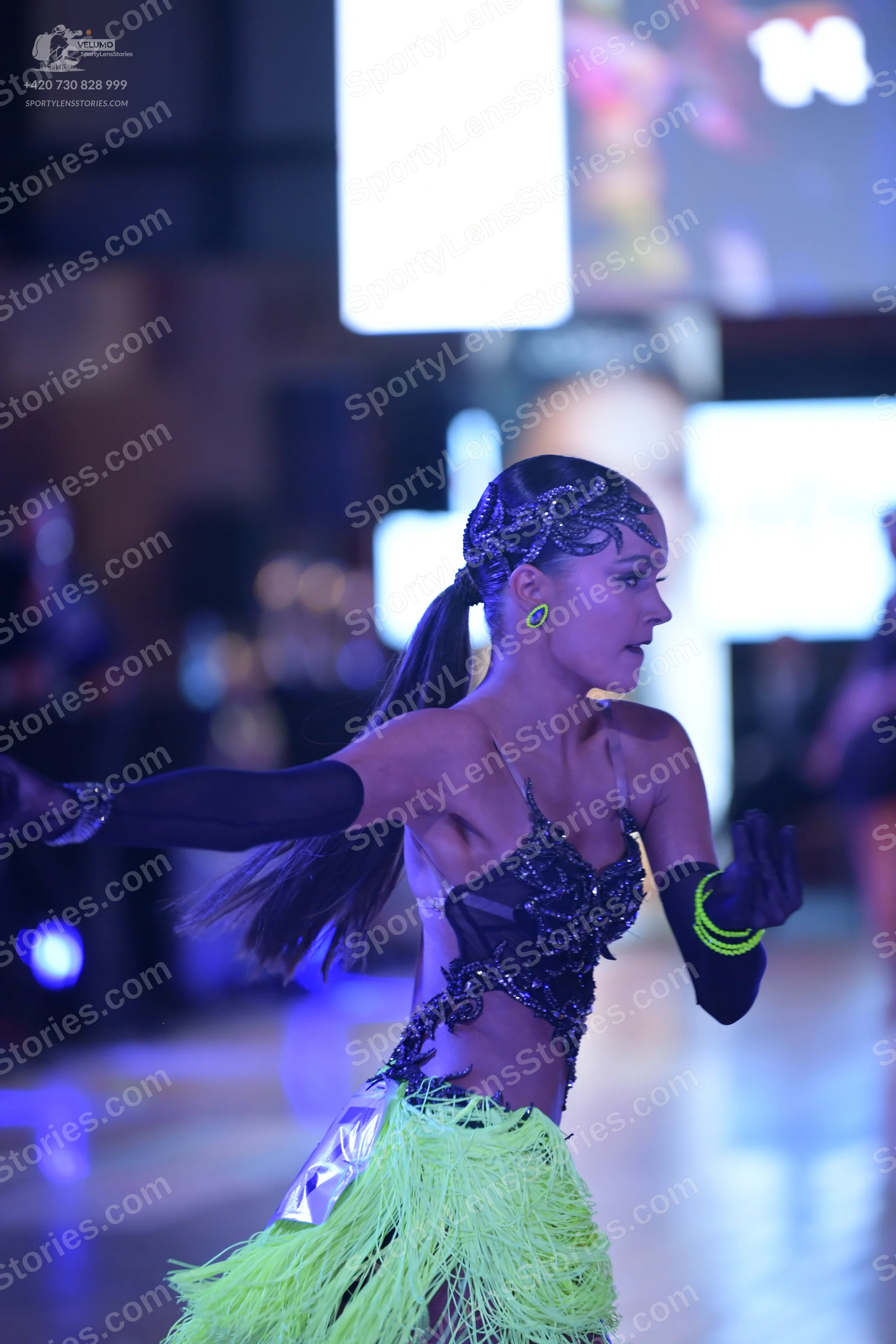 Dancesport competitor: Female dancer: lime green Latin dance skirt with fringe, dark sequined top with 
