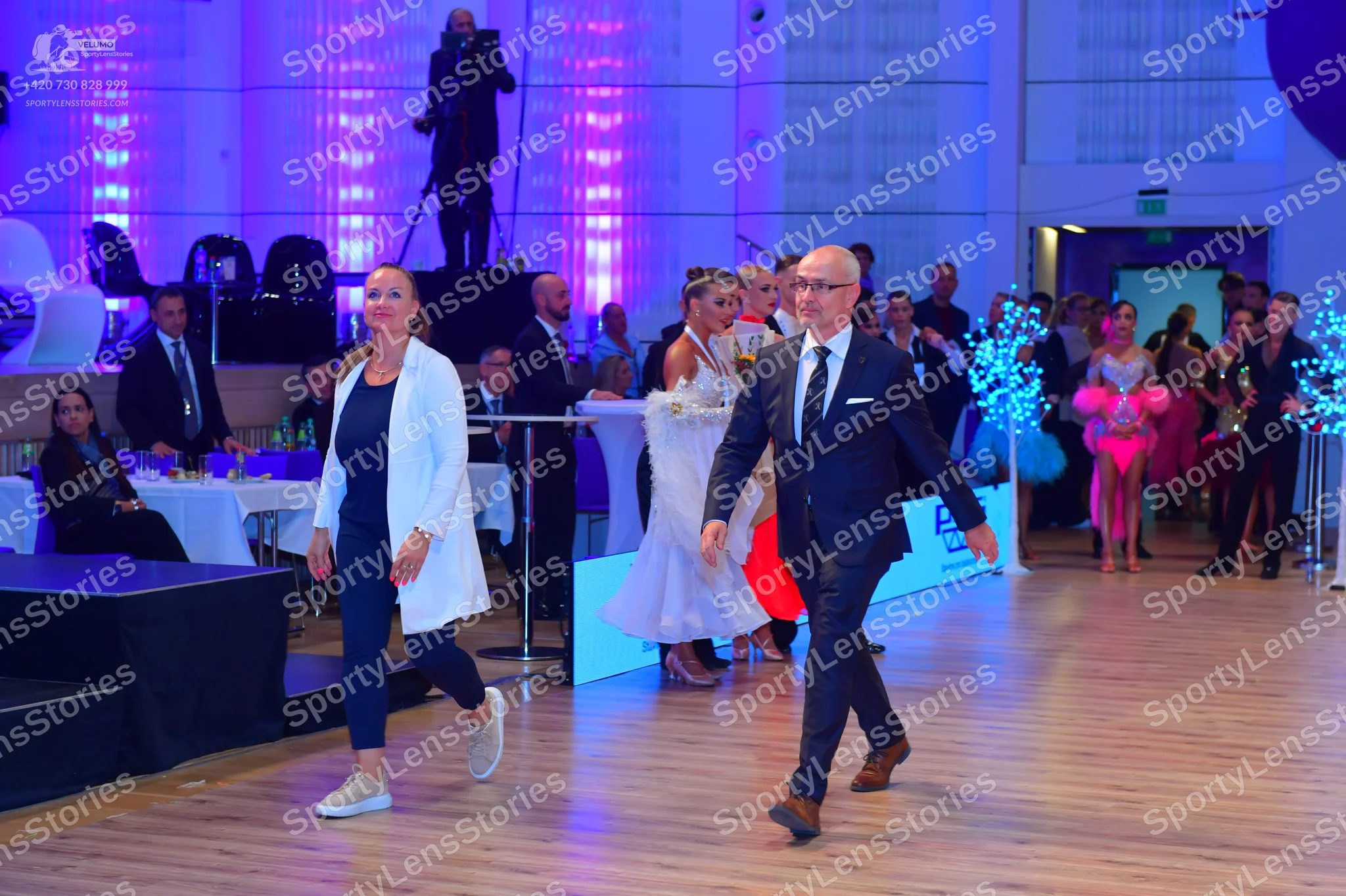 Dancesport competitor: Female dancer in background: white ballgown