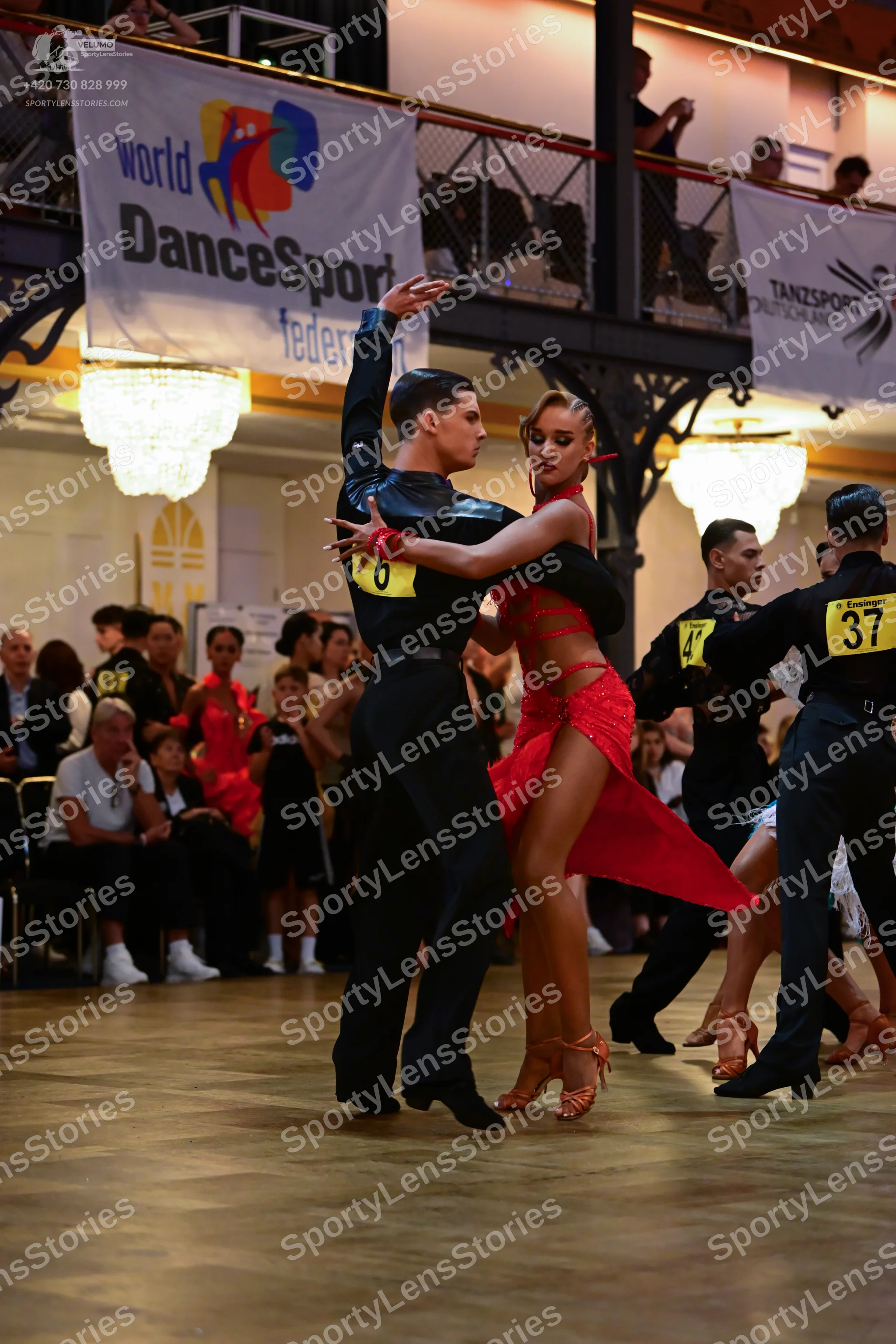 Dancesport competitor: Male dancer in foreground: black long-sleeved shirt and black trousers