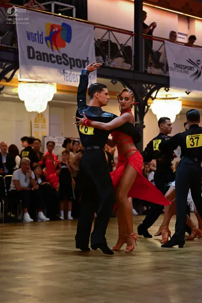 Dancesport competitor: Male dancer in foreground: black long-sleeved shirt and black trousers