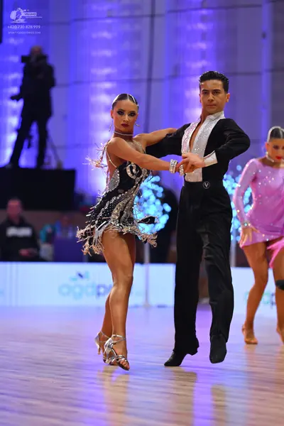 Dancesport competitor: Male dancer: black long-sleeve shirt with a white V-shaped panel on the chest an