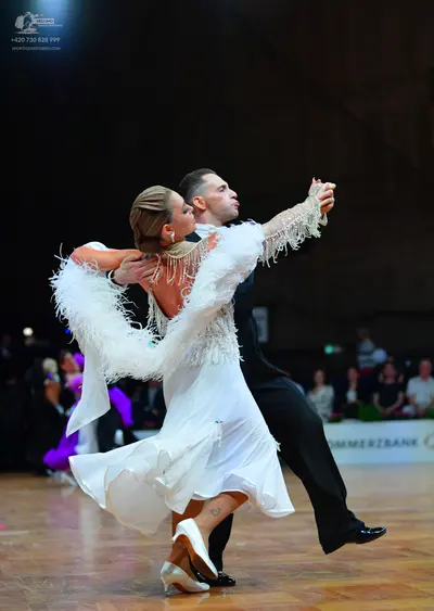 Dancesport competitor: Female dancer: white dance dress with large white feather/fringe trim on the sle
