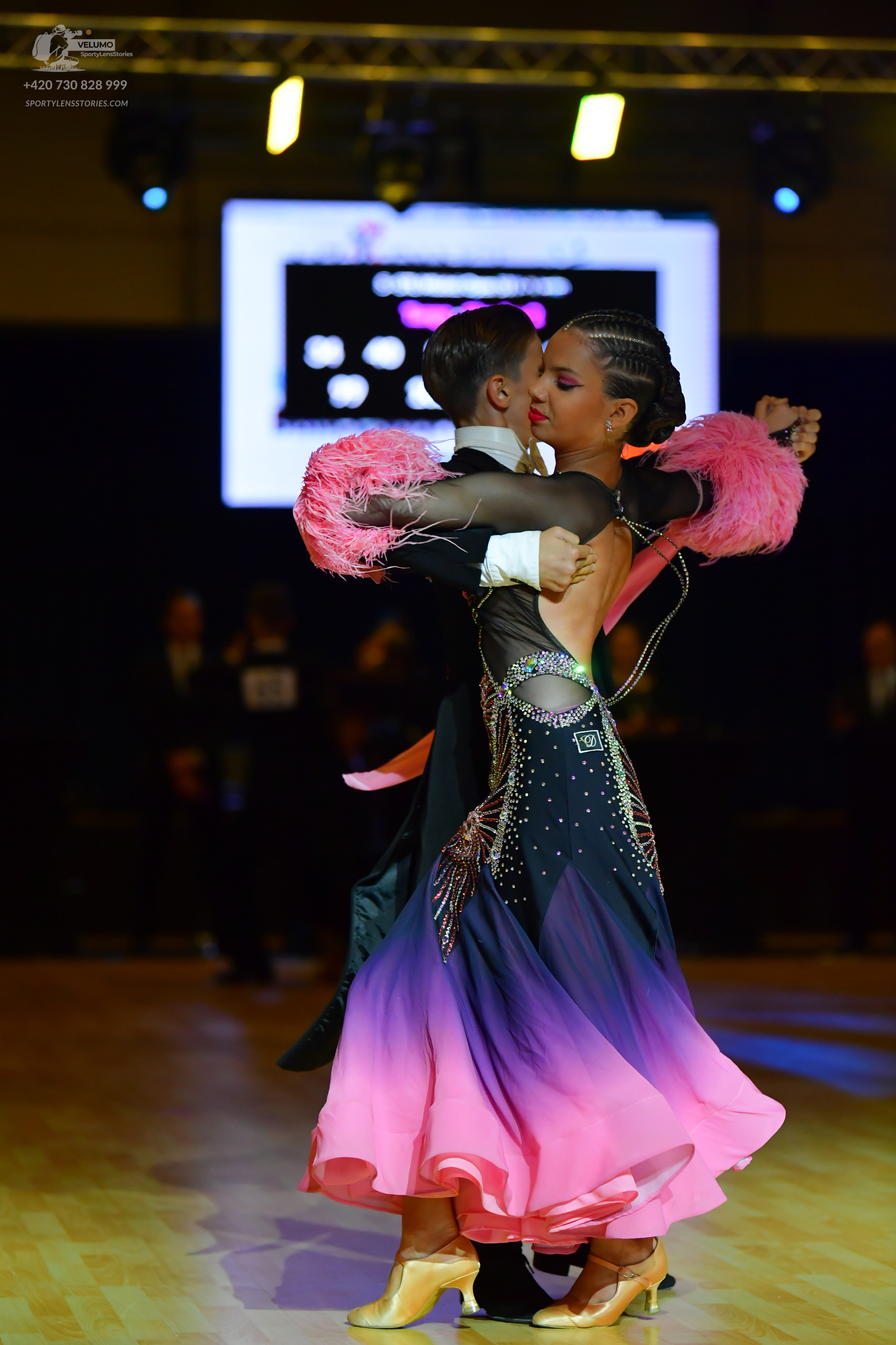 Dancesport competitor: Female dancer: black, purple, and pink ombre ballgown with a sheer, crystal-embe