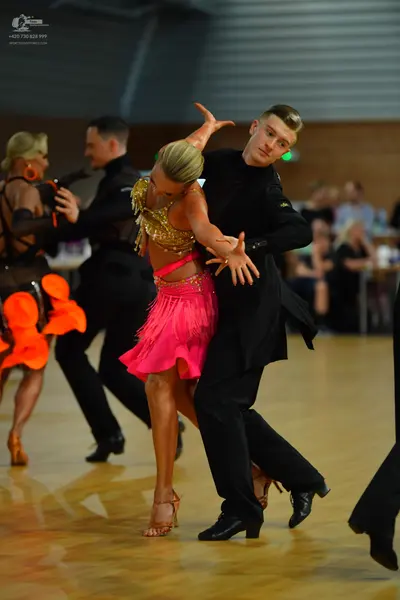 Dancesport competitor: Main female dancer: gold sequin top and pink fringed Latin skirt