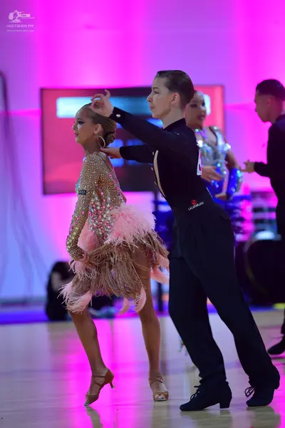 Dancesport competitor: Female dancer (foreground): nude-colored latin dress embellished with sequins an