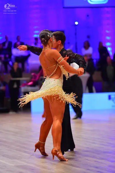 Dancesport competitor: Female dancer: champagne-colored Latin dress embellished with sequins, featuring
