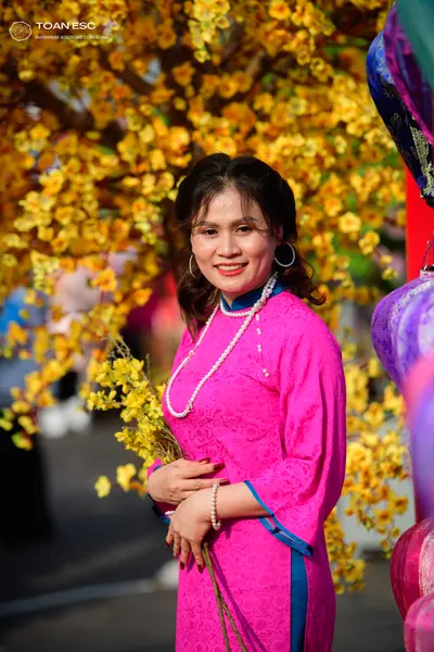 Dancesport competitor: Female dancer: pink Áo dài with a floral pattern and dark blue/teal trim, access