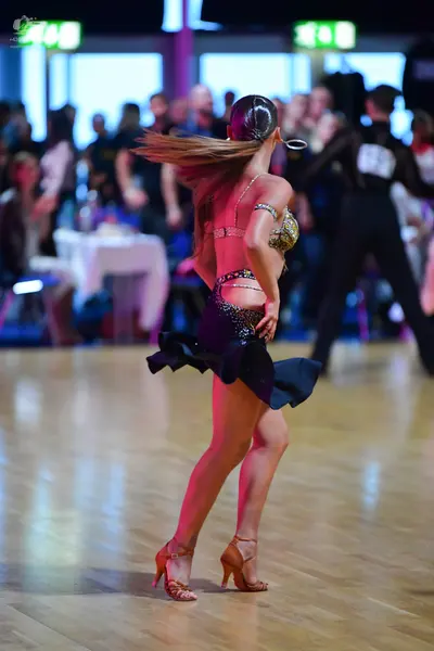 Dancesport competitor: Female dancer: Gold and bronze sequined Latin-style top and waistband with a bla