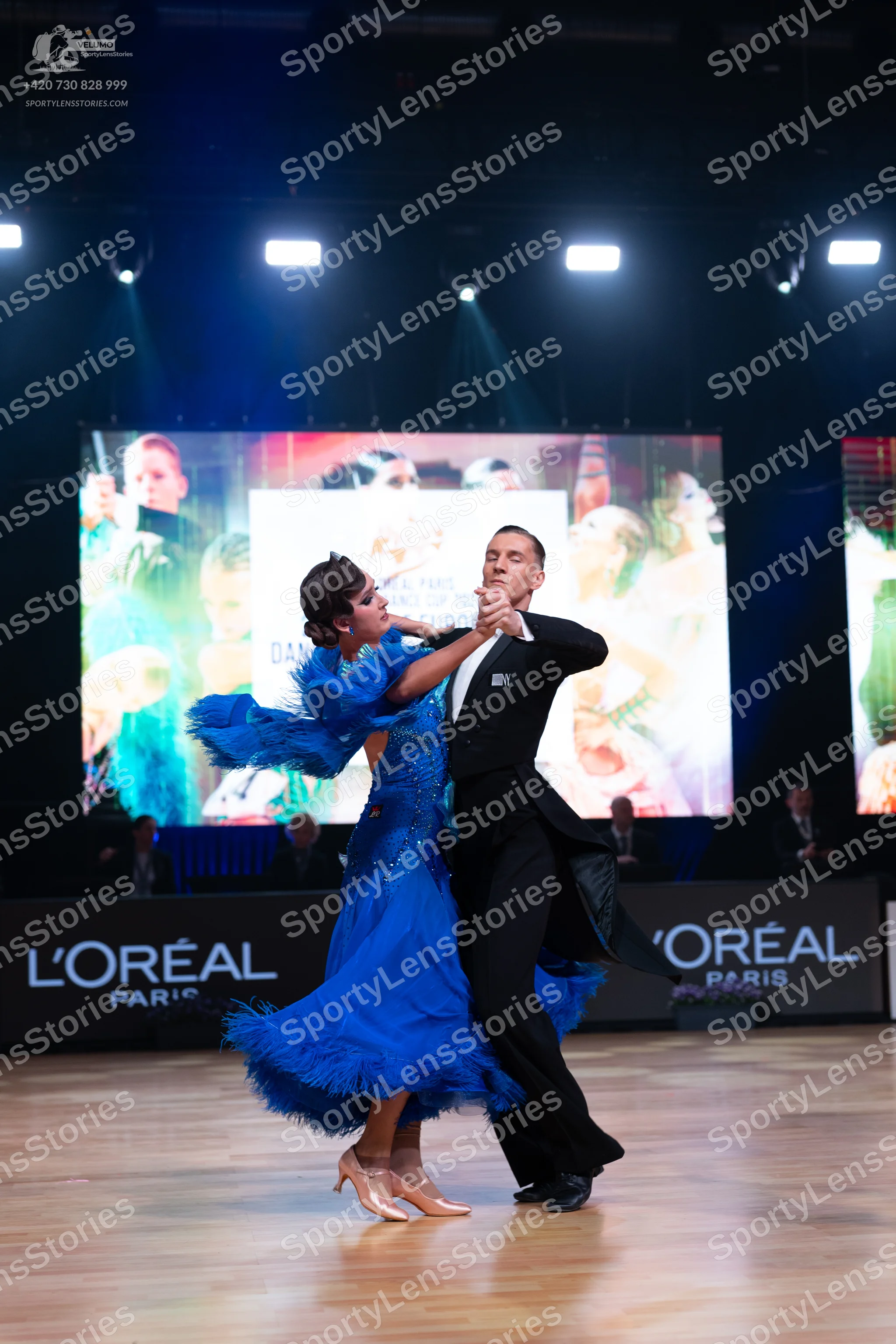 Dancesport competitor: Female dancer: bright blue ballgown with a voluminous ruffled/feathered skirt an