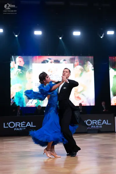 Dancesport competitor: Female dancer: bright blue ballgown with a voluminous ruffled/feathered skirt an