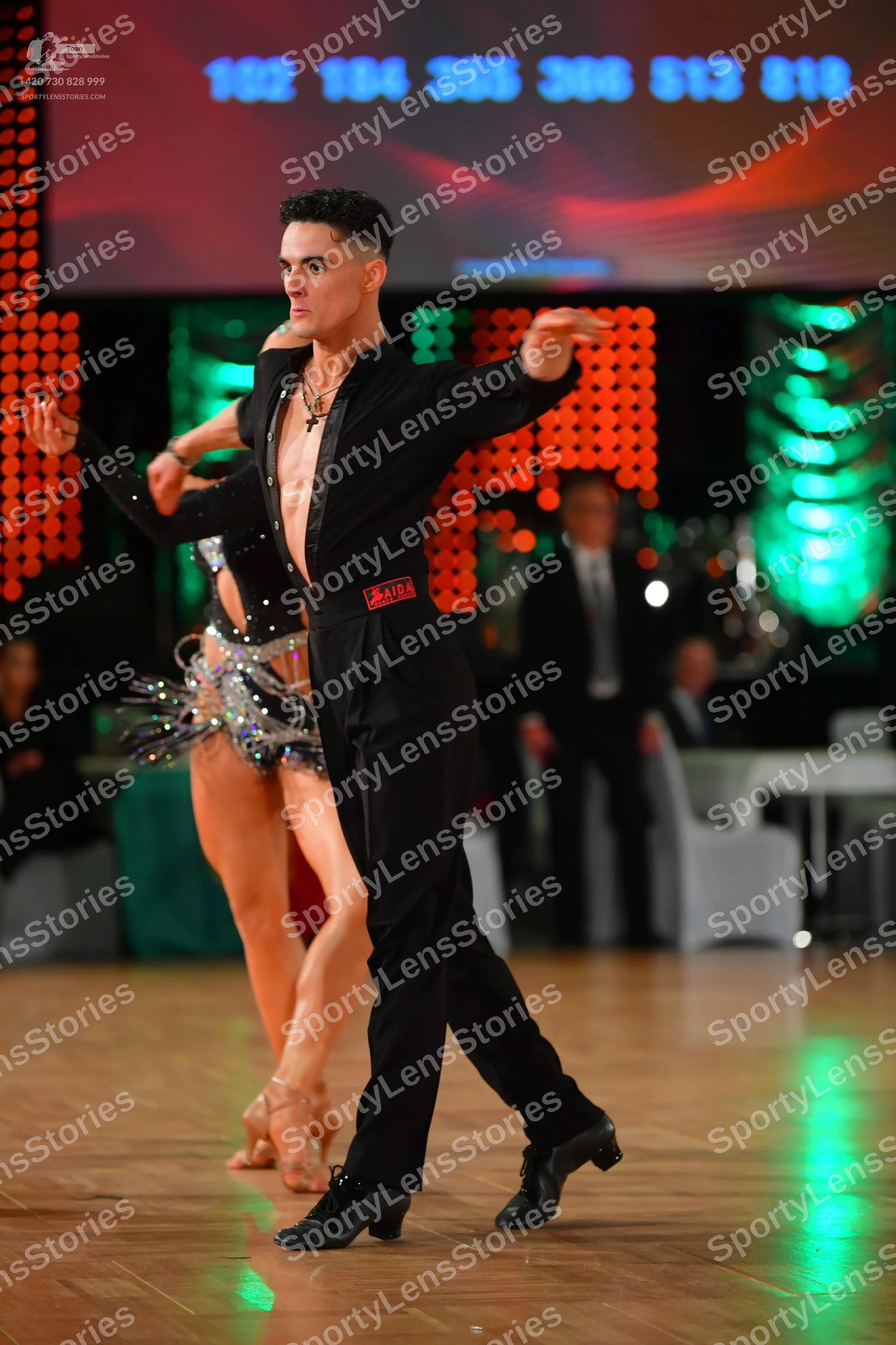 Dancesport competitor: Male dancer: black long-sleeved shirt, open at the chest, and black trousers, we
