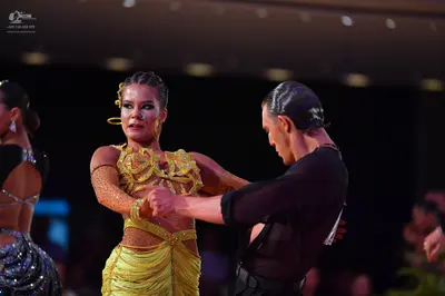 Dancesport competitor: Female dancer (center): yellow Latin dance dress with sequins and intricate cuto
