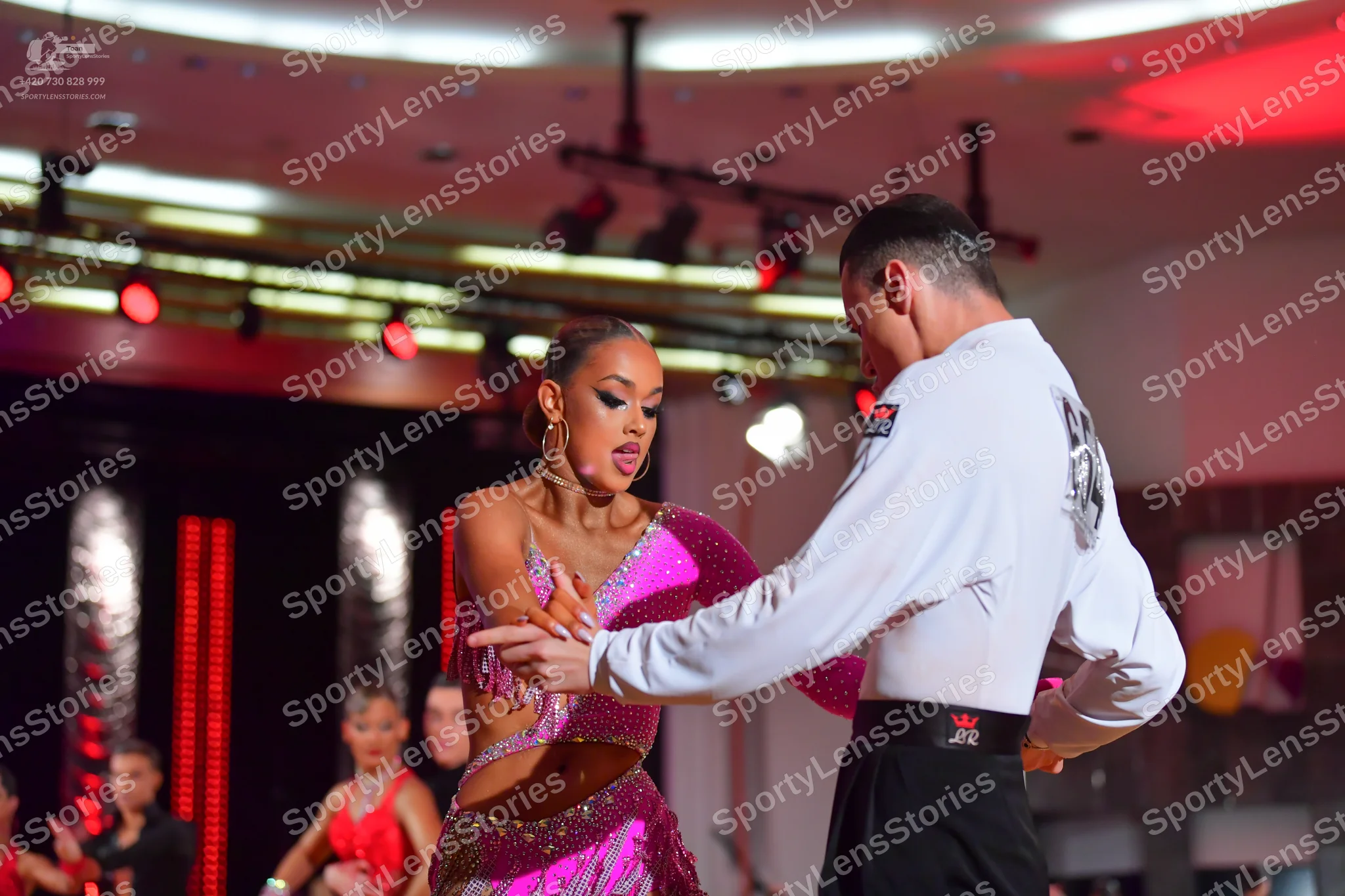 Dancesport competitor: Main female dancer: purple/magenta sequined Latin dress with side cutouts