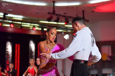 Dancesport competitor: Main female dancer: purple/magenta sequined Latin dress with side cutouts
