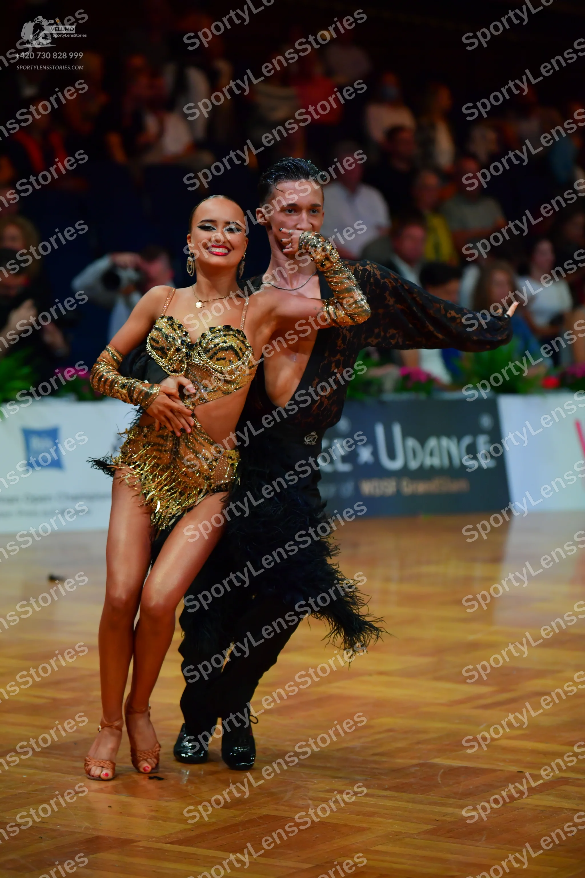 Dancesport competitor: Female dancer: gold sequined Latin dance bodysuit with metallic texture and frin