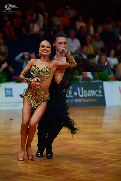 Dancesport competitor: Female dancer: gold sequined Latin dance bodysuit with metallic texture and frin