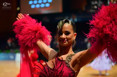 Dancesport competitor: Female dancer: magenta latin dress with voluminous pink feathered sleeves and a 
