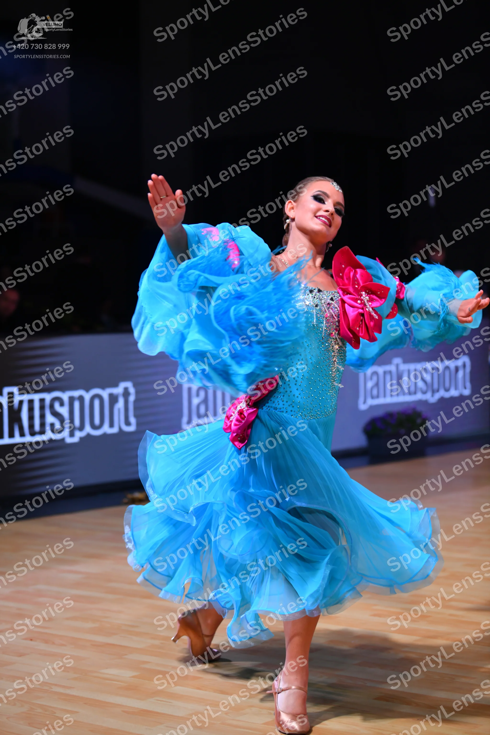 Dancesport competitor: Female dancer: light blue voluminous ruffled dance dress with pink fabric accent