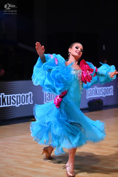 Dancesport competitor: Female dancer: light blue voluminous ruffled dance dress with pink fabric accent
