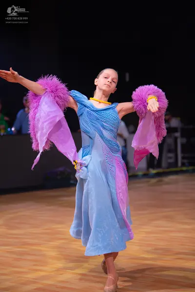 Dancesport competitor: Female dancer: light blue and pink Latin dance dress with feathery, fringed slee