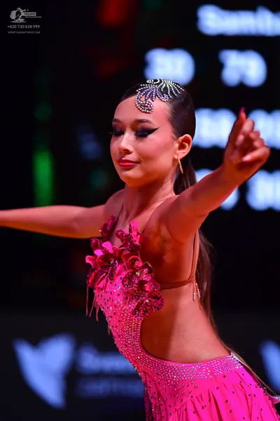 Dancesport competitor: Female dancer: bright pink latin dress adorned with rhinestones and 3D floral em