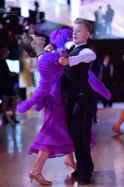 Dancesport competitor: Female dancer: purple latin dress with long fringe on the sleeves and bodice, an