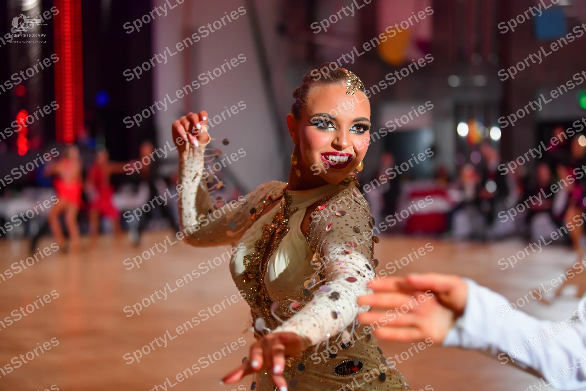 Dancesport competitor: Female dancer in foreground: nude-colored, long-sleeved dance dress with heavy s