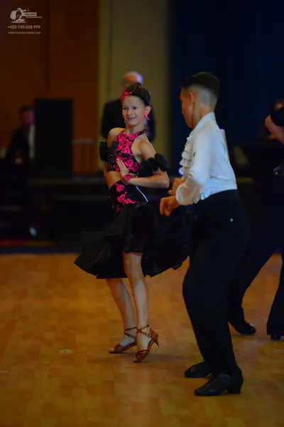 Dancesport competitor: Female dancer: pink and black Latin dance costume with sequin/beaded details on 