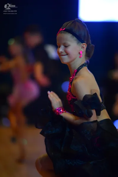 Dancesport competitor: Foreground female dancer: black ballroom dress with a voluminous skirt and pink/
