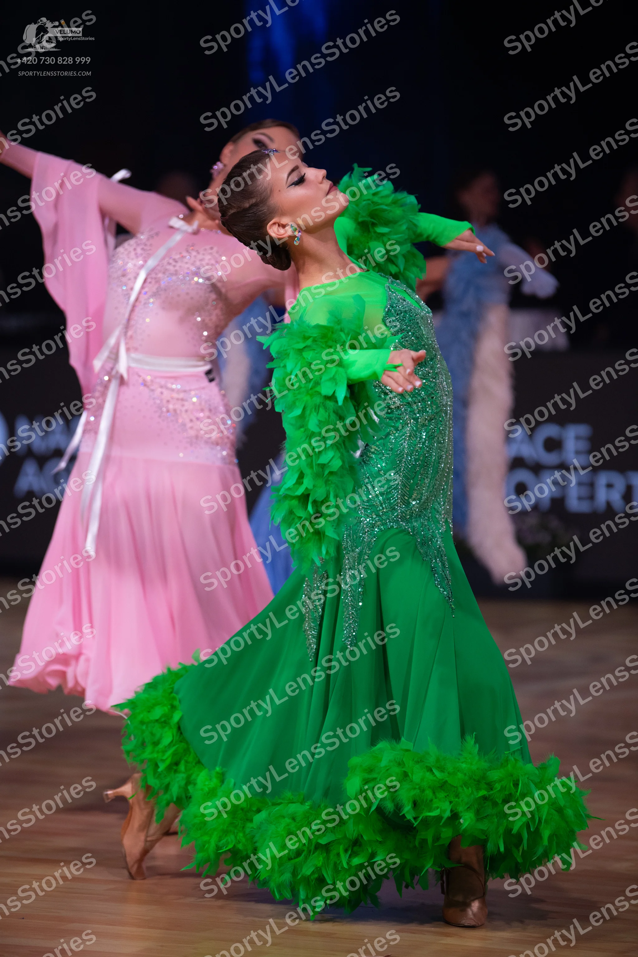 Dancesport competitor: Female dancer in foreground: bright green standard dance dress with a sequined b