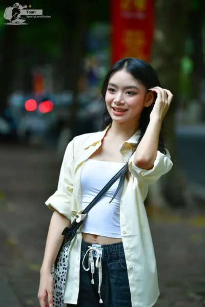 Dancesport competitor: Female dancer: white tank top, light cream-colored button-down shirt, and dark d