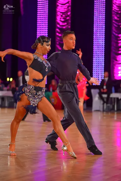 Dancesport competitor: Female dancer: dark navy or black latin dance costume heavily embellished with s