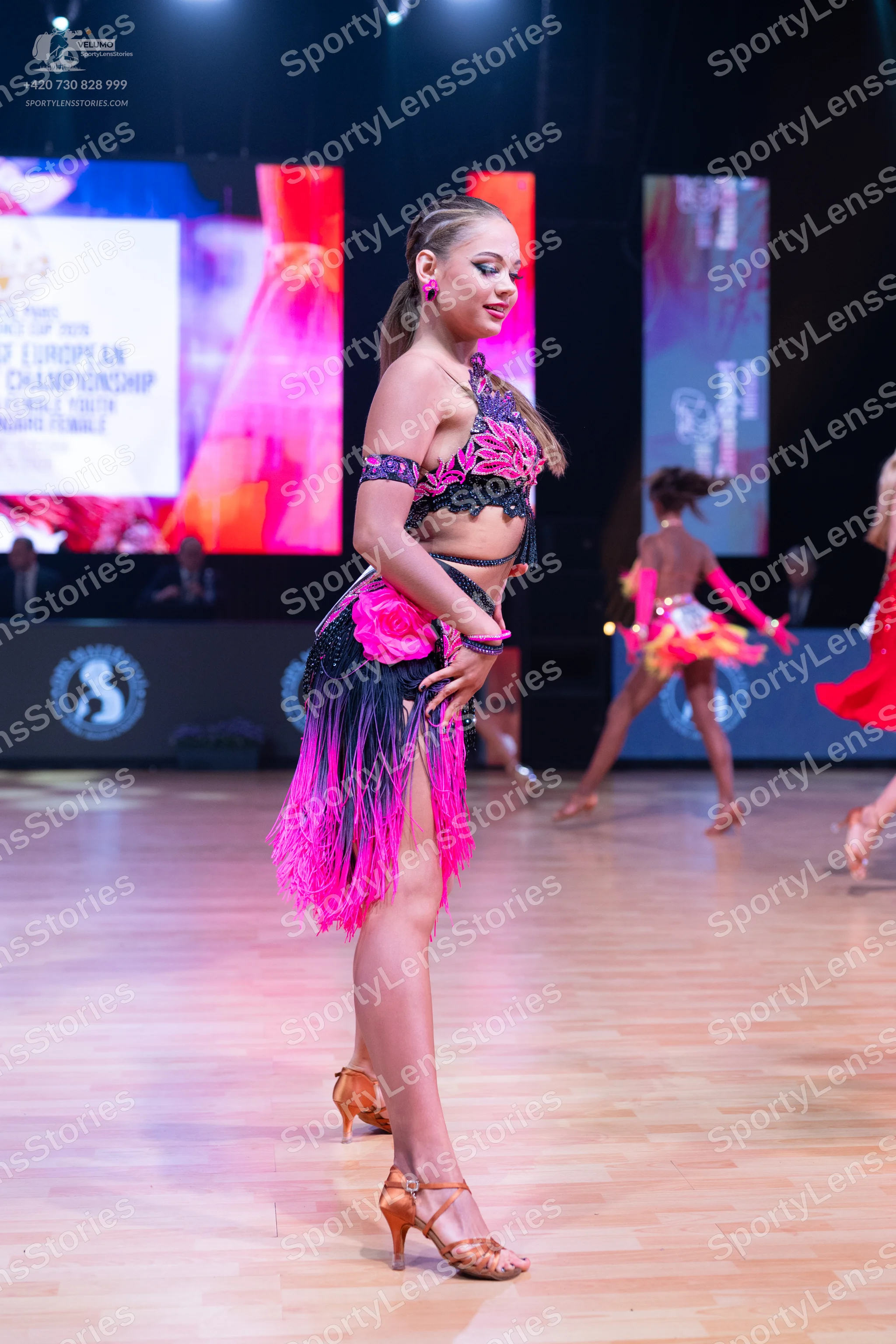 Dancesport competitor: Main dancer: pink and black Latin dance costume featuring a black top with lace/