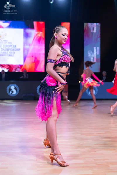 Dancesport competitor: Main dancer: pink and black Latin dance costume featuring a black top with lace/