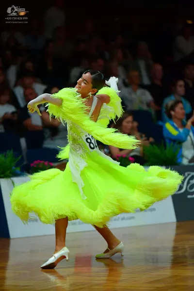 Dancesport competitor: Female dancer: neon yellow/lime green ballgown with a large, voluminous ruffled 